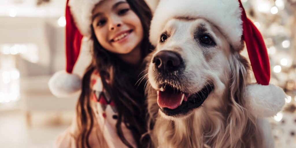 girl with dog wearing santa hats